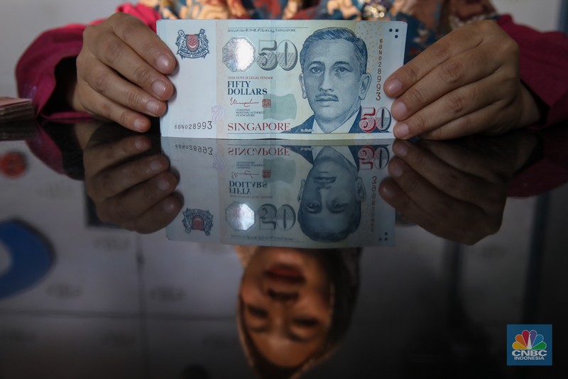 Petugas menjunjukkan mata uang Dolar Singapura di VIP Money Changer, Jakarta, Kamis (25/9/2025). (CNBC Indonesia/Faisal Rahman)
