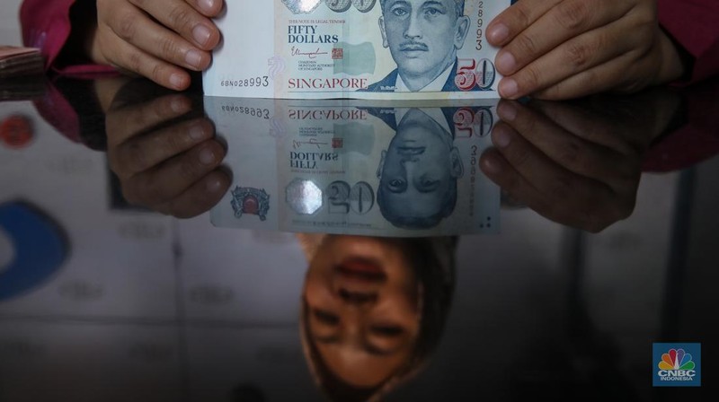 Petugas menjunjukkan mata uang Dolar Singapura di VIP Money Changer, Jakarta, Kamis (25/9/2025). (CNBC Indonesia/Faisal Rahman)