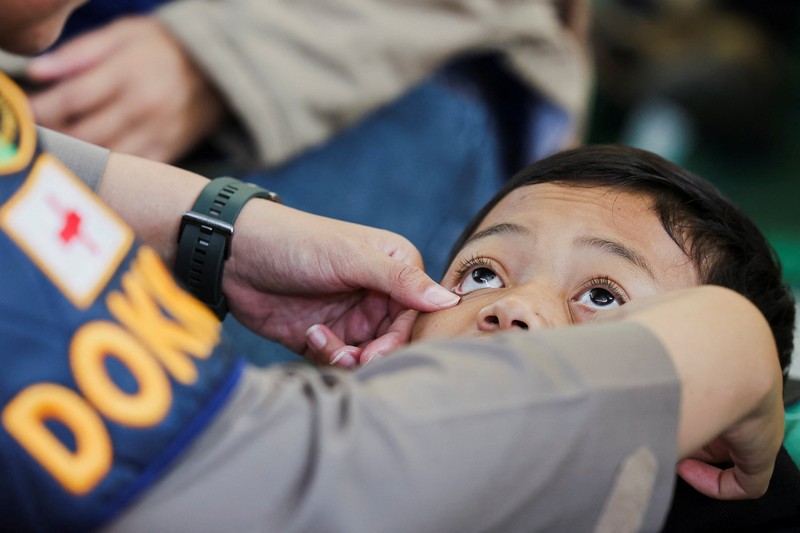 Muhammad Setiawan Pratama, 11, seorang siswa sekolah dasar menerima perawatan keracunan makanan setelah makan makanan sekolah gratis yang disponsori pemerintah, di sebuah klinik darurat di dalam aula kabupaten di Bandung, provinsi Jawa Barat, Indonesia, 25 September 2025. (REUTERS/Willy Kurniawan)