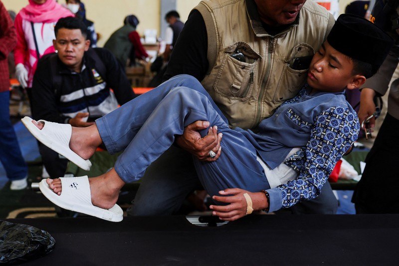 Muhammad Setiawan Pratama, 11, seorang siswa sekolah dasar menerima perawatan keracunan makanan setelah makan makanan sekolah gratis yang disponsori pemerintah, di sebuah klinik darurat di dalam aula kabupaten di Bandung, provinsi Jawa Barat, Indonesia, 25 September 2025. (REUTERS/Willy Kurniawan)