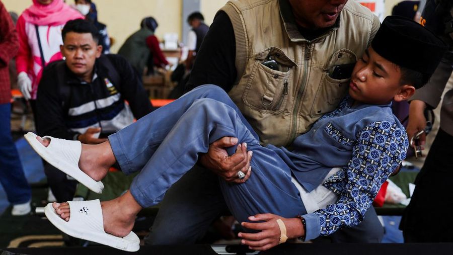Muhammad Setiawan Pratama, 11, seorang siswa sekolah dasar menerima perawatan keracunan makanan setelah makan makanan sekolah gratis yang disponsori pemerintah, di sebuah klinik darurat di dalam aula kabupaten di Bandung, provinsi Jawa Barat, Indonesia, 25 September 2025. (REUTERS/Willy Kurniawan)