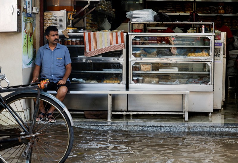 Orang-orang berjalan melalui jalan yang tergenang air setelah hujan deras di Kolkata, India, 24 September 2025. (REUTERS/Sahiba Chawdhary)
