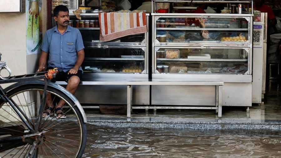 Orang-orang berjalan melalui jalan yang tergenang air setelah hujan deras di Kolkata, India, 24 September 2025. (REUTERS/Sahiba Chawdhary)