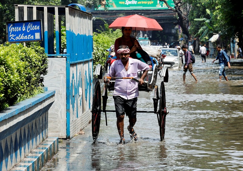Orang-orang berjalan melalui jalan yang tergenang air setelah hujan deras di Kolkata, India, 24 September 2025. (REUTERS/Sahiba Chawdhary)