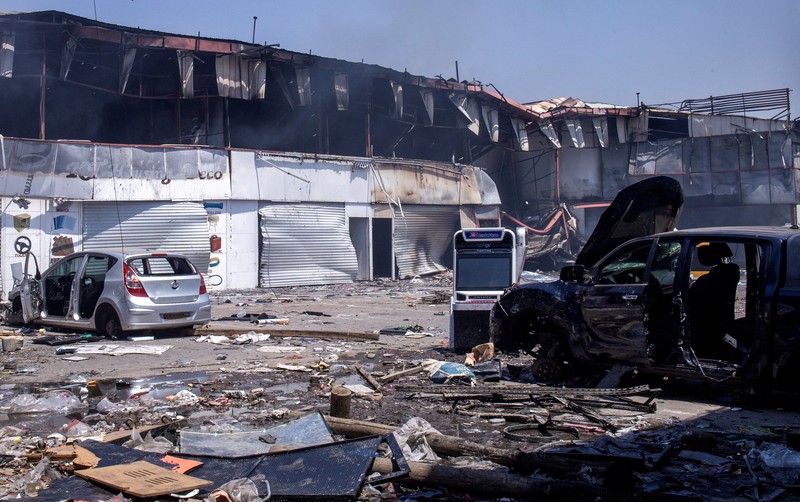 Para pekerja menyelamatkan barang-barang mereka dari toko yang terbakar selama demonstrasi untuk mengecam seringnya pemadaman listrik dan kekurangan air di Antananarivo, Madagaskar, 25 September 2025. (REUTERS/Zo Andrianjafy)