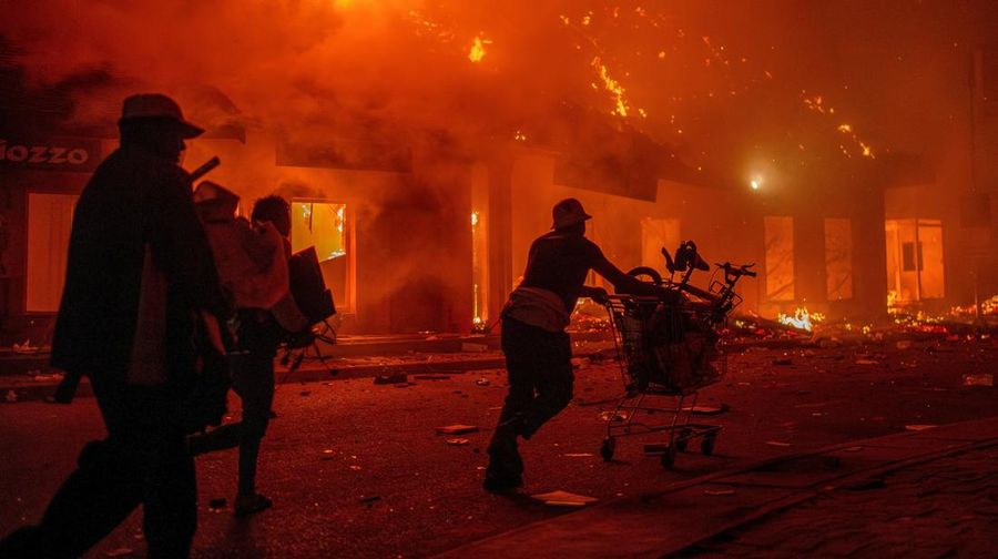 Para pekerja menyelamatkan barang-barang mereka dari toko yang terbakar selama demonstrasi untuk mengecam seringnya pemadaman listrik dan kekurangan air di Antananarivo, Madagaskar, 25 September 2025. (REUTERS/Zo Andrianjafy)