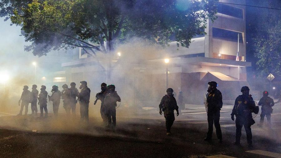 Gas air mata dan asap menyelimuti agen ICE saat orang-orang memprotes kebijakan imigrasi pemerintahan Presiden AS Donald Trump, di luar fasilitas penahanan ICE di Portland, Oregon, AS, 1 September 2025. (REUTERS/John Rudoff)