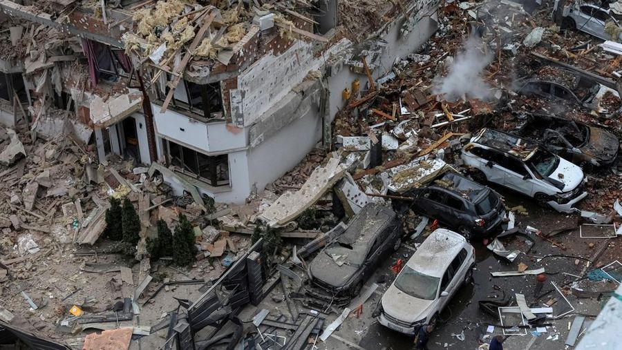 Orang-orang berjalan di samping bangunan dan kendaraan yang rusak di lingkungan perumahan yang terkena serangan pesawat tak berawak dan rudal Rusia, di tengah serangan Rusia terhadap Ukraina, di pinggiran Kyiv, Ukraina, 28 September 2025. (REUTERS/Anatolii Stepanov)