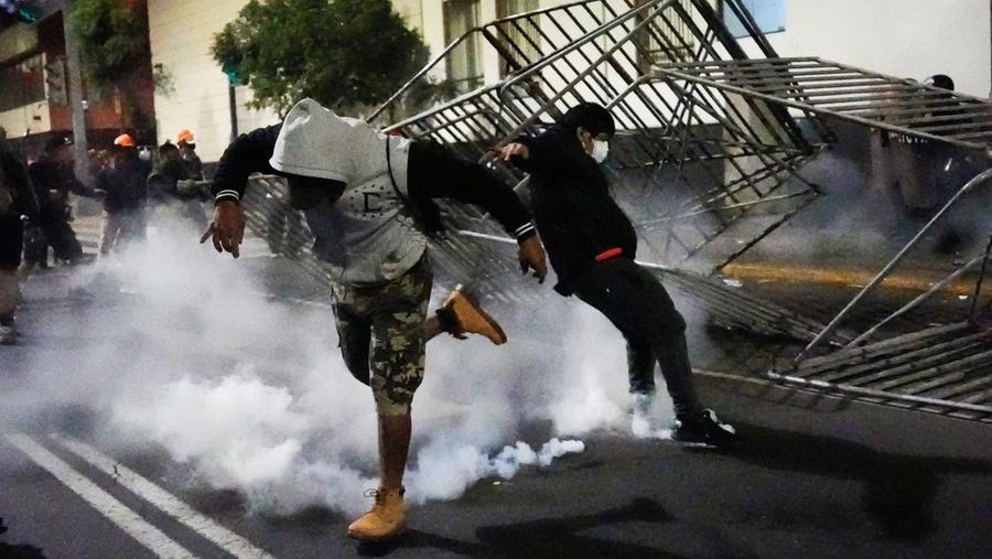 Para pengunjuk rasa mengangkat figur berbentuk tengkorak dengan tulisan 