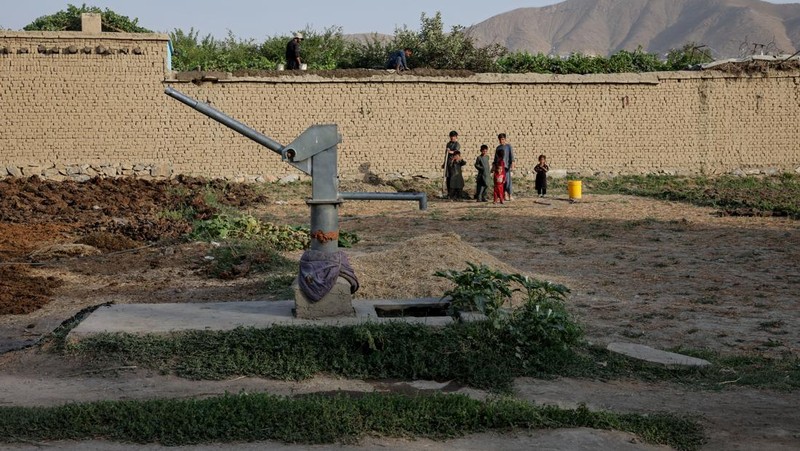 Assadullah, 42, dan anak laki-laki berkumpul di dekat keran air untuk mengambil air, di tengah krisis air yang serius di Kabul, Afghanistan, 28 Agustus 2025. (REUTERS/Sayed Hassib)