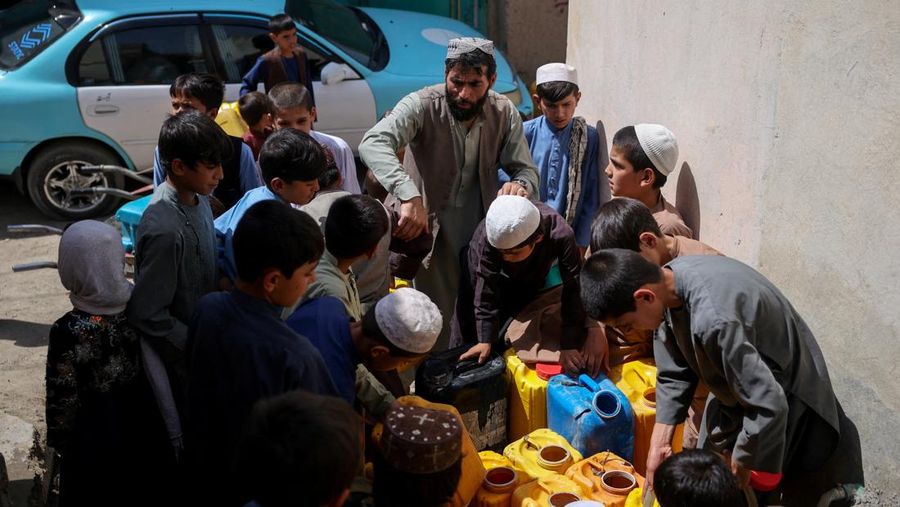 Assadullah, 42, dan anak laki-laki berkumpul di dekat keran air untuk mengambil air, di tengah krisis air yang serius di Kabul, Afghanistan, 28 Agustus 2025. (REUTERS/Sayed Hassib)
