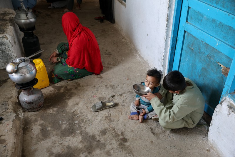 Assadullah, 42, dan anak laki-laki berkumpul di dekat keran air untuk mengambil air, di tengah krisis air yang serius di Kabul, Afghanistan, 28 Agustus 2025. (REUTERS/Sayed Hassib)