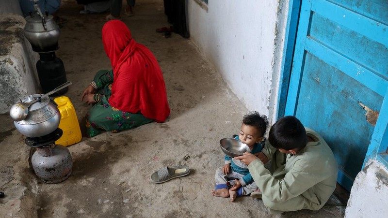 Assadullah, 42, dan anak laki-laki berkumpul di dekat keran air untuk mengambil air, di tengah krisis air yang serius di Kabul, Afghanistan, 28 Agustus 2025. (REUTERS/Sayed Hassib)