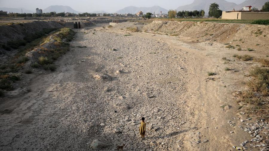 Assadullah, 42, dan anak laki-laki berkumpul di dekat keran air untuk mengambil air, di tengah krisis air yang serius di Kabul, Afghanistan, 28 Agustus 2025. (REUTERS/Sayed Hassib)