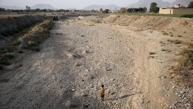 Assadullah, 42, dan anak laki-laki berkumpul di dekat keran air untuk mengambil air, di tengah krisis air yang serius di Kabul, Afghanistan, 28 Agustus 2025. (REUTERS/Sayed Hassib)