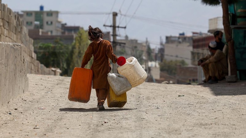 Assadullah, 42, dan anak laki-laki berkumpul di dekat keran air untuk mengambil air, di tengah krisis air yang serius di Kabul, Afghanistan, 28 Agustus 2025. (REUTERS/Sayed Hassib)