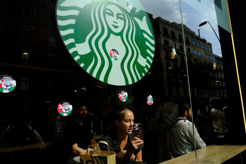 Seorang mahasiswa berunjuk rasa di depan kedai kopi Starbucks selama protes pro-Palestina untuk mengutuk intersepsi pasukan Israel terhadap kapal-kapal Armada Global Sumud yang bertujuan mencapai Gaza dan menerobos blokade laut Israel, di Barcelona, Spanyol, 2 Oktober 2025. Seorang mahasiswa berunjuk rasa di depan kedai kopi Starbucks selama protes pro-Palestina untuk mengutuk intersepsi pasukan Israel terhadap kapal-kapal Armada Global Sumud yang bertujuan mencapai Gaza dan menerobos blokade laut Israel, di Barcelona, Spanyol, 2 Oktober 2025. (REUTERS/Nacho Doce)