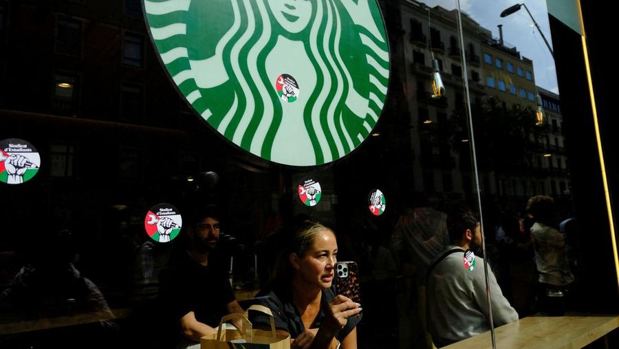 Seorang mahasiswa berunjuk rasa di depan kedai kopi Starbucks selama protes pro-Palestina untuk mengutuk intersepsi pasukan Israel terhadap kapal-kapal Armada Global Sumud yang bertujuan mencapai Gaza dan menerobos blokade laut Israel, di Barcelona, ​​Spanyol, 2 Oktober 2025. (REUTERS/Nacho Doce)