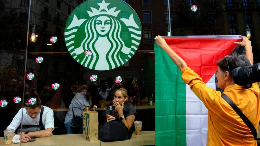 Seorang mahasiswa berunjuk rasa di depan kedai kopi Starbucks selama protes pro-Palestina untuk mengutuk intersepsi pasukan Israel terhadap kapal-kapal Armada Global Sumud yang bertujuan mencapai Gaza dan menerobos blokade laut Israel, di Barcelona, ​​Spanyol, 2 Oktober 2025. (REUTERS/Nacho Doce)