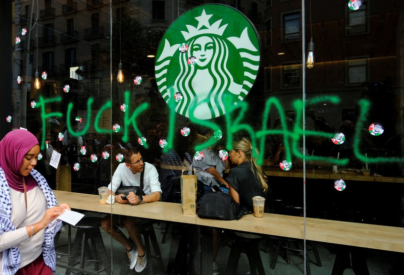 Seorang mahasiswa berunjuk rasa di depan kedai kopi Starbucks selama protes pro-Palestina untuk mengutuk intersepsi pasukan Israel terhadap kapal-kapal Armada Global Sumud yang bertujuan mencapai Gaza dan menerobos blokade laut Israel, di Barcelona, Spanyol, 2 Oktober 2025. Seorang mahasiswa berunjuk rasa di depan kedai kopi Starbucks selama protes pro-Palestina untuk mengutuk intersepsi pasukan Israel terhadap kapal-kapal Armada Global Sumud yang bertujuan mencapai Gaza dan menerobos blokade laut Israel, di Barcelona, Spanyol, 2 Oktober 2025. (REUTERS/Nacho Doce)