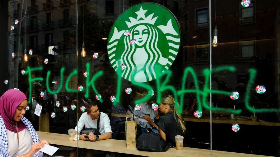 Seorang mahasiswa berunjuk rasa di depan kedai kopi Starbucks selama protes pro-Palestina untuk mengutuk intersepsi pasukan Israel terhadap kapal-kapal Armada Global Sumud yang bertujuan mencapai Gaza dan menerobos blokade laut Israel, di Barcelona, ​​Spanyol, 2 Oktober 2025. (REUTERS/Nacho Doce)