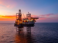 Aerial view of silhouette offshore jack up drilling rig during sunset - oil and gas industry