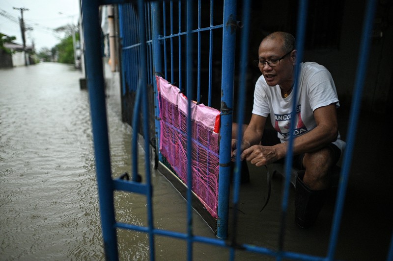 Seorang wanita berjalan melewati jalan yang banjir setelah hujan, yang diperparah oleh Badai Tropis Matmo, di Santa Lucia, Calumpit, provinsi Bulacan, Filipina, 3 Oktober 2025. (REUTERS/Noel Celis)