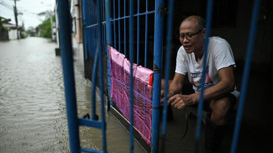 Seorang wanita berjalan melewati jalan yang banjir setelah hujan, yang diperparah oleh Badai Tropis Matmo, di Santa Lucia, Calumpit, provinsi Bulacan, Filipina, 3 Oktober 2025. (REUTERS/Noel Celis)