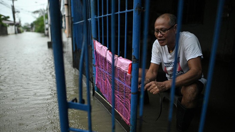 Seorang wanita berjalan melewati jalan yang banjir setelah hujan, yang diperparah oleh Badai Tropis Matmo, di Santa Lucia, Calumpit, provinsi Bulacan, Filipina, 3 Oktober 2025. (REUTERS/Noel Celis)
