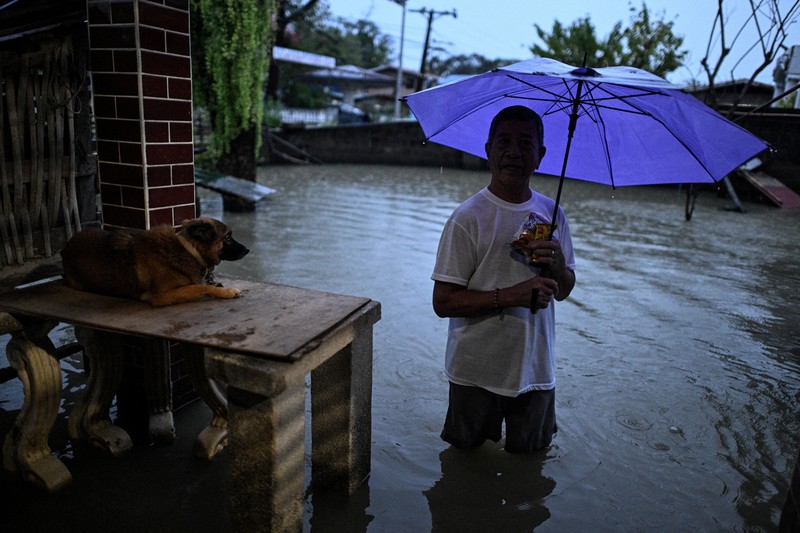 Seorang wanita berjalan melewati jalan yang banjir setelah hujan, yang diperparah oleh Badai Tropis Matmo, di Santa Lucia, Calumpit, provinsi Bulacan, Filipina, 3 Oktober 2025. (REUTERS/Noel Celis)