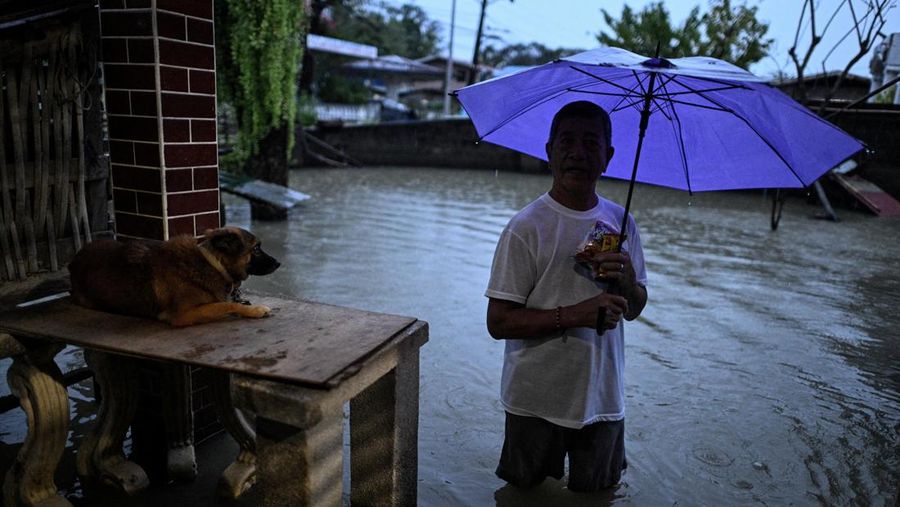 Seorang wanita berjalan melewati jalan yang banjir setelah hujan, yang diperparah oleh Badai Tropis Matmo, di Santa Lucia, Calumpit, provinsi Bulacan, Filipina, 3 Oktober 2025. (REUTERS/Noel Celis)