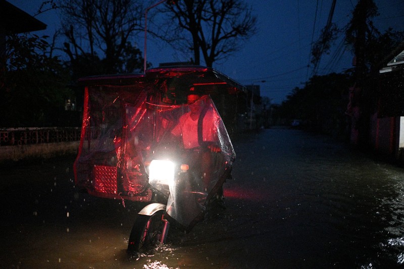 Seorang wanita berjalan melewati jalan yang banjir setelah hujan, yang diperparah oleh Badai Tropis Matmo, di Santa Lucia, Calumpit, provinsi Bulacan, Filipina, 3 Oktober 2025. (REUTERS/Noel Celis)