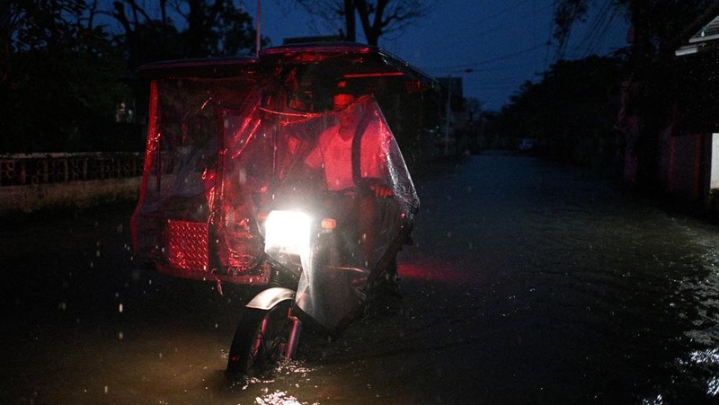 Seorang wanita berjalan melewati jalan yang banjir setelah hujan, yang diperparah oleh Badai Tropis Matmo, di Santa Lucia, Calumpit, provinsi Bulacan, Filipina, 3 Oktober 2025. (REUTERS/Noel Celis)