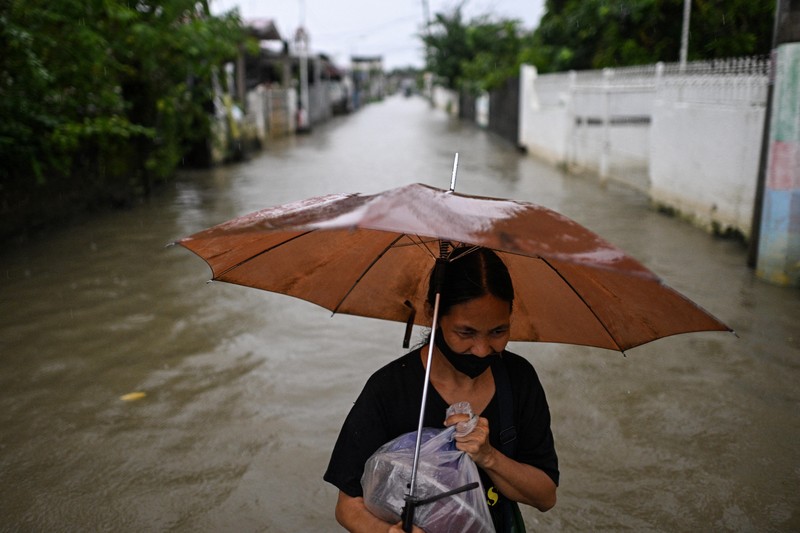 Seorang wanita berjalan melewati jalan yang banjir setelah hujan, yang diperparah oleh Badai Tropis Matmo, di Santa Lucia, Calumpit, provinsi Bulacan, Filipina, 3 Oktober 2025. (REUTERS/Noel Celis)