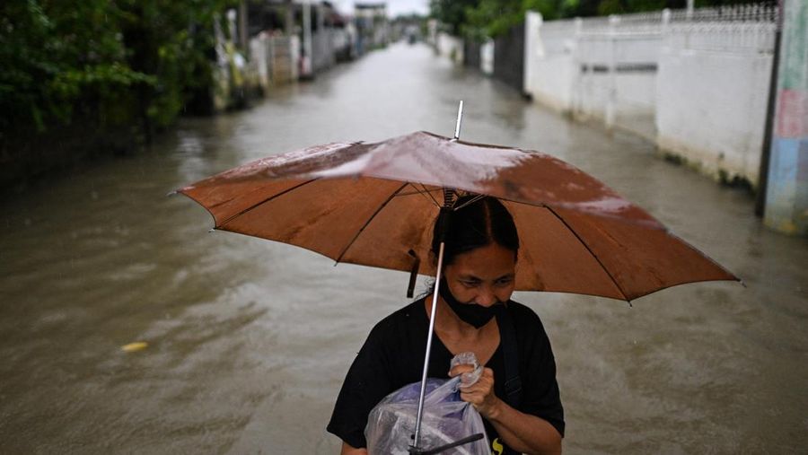 Seorang wanita berjalan melewati jalan yang banjir setelah hujan, yang diperparah oleh Badai Tropis Matmo, di Santa Lucia, Calumpit, provinsi Bulacan, Filipina, 3 Oktober 2025. (REUTERS/Noel Celis)