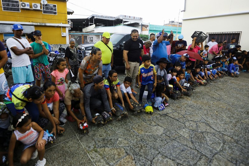 Seorang anak memegang Morrocoye, kura-kura darat asli Amerika Selatan, sebelum perlombaan kura-kura yang diadakan untuk merayakan hari raya Santo Fransiskus dari Assisi, santo pelindung hewan, di kota San Francisco de Asis, Venezuela, 3 Oktober 2025. (REUTERS/Juan Carlos Hernandez)