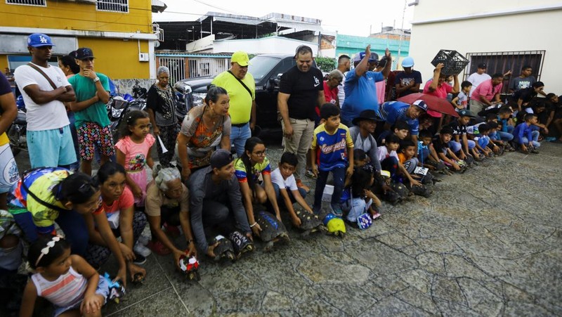 Seorang anak memegang Morrocoye, kura-kura darat asli Amerika Selatan, sebelum perlombaan kura-kura yang diadakan untuk merayakan hari raya Santo Fransiskus dari Assisi, santo pelindung hewan, di kota San Francisco de Asis, Venezuela, 3 Oktober 2025. (REUTERS/Juan Carlos Hernandez)