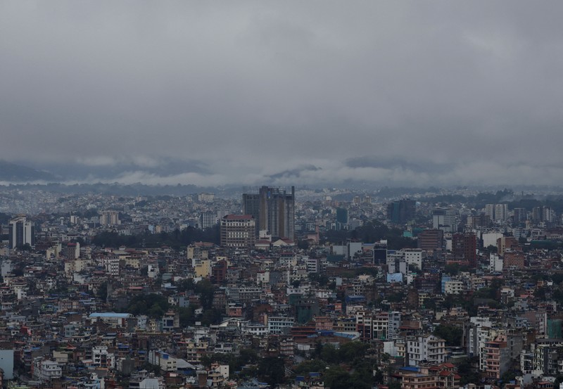 Seorang pria membawa payung berjalan melewati grafiti bertuliskan 'Nepal' di jalan yang banjir di sepanjang tepi Sungai Bagmati yang meluap setelah hujan lebat, di Kathmandu, Nepal, 4 Oktober 2025. (REUTERS/Navesh Chitrakar)