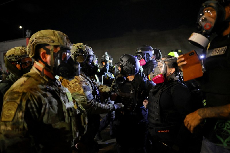 Para pengunjuk rasa berhadapan dengan petugas penegak hukum di luar markas besar Imigrasi dan Penegakan Bea Cukai AS (ICE) di Portland, Oregon, AS, 4 Oktober 2025. (REUTERS/Carlos Barria)