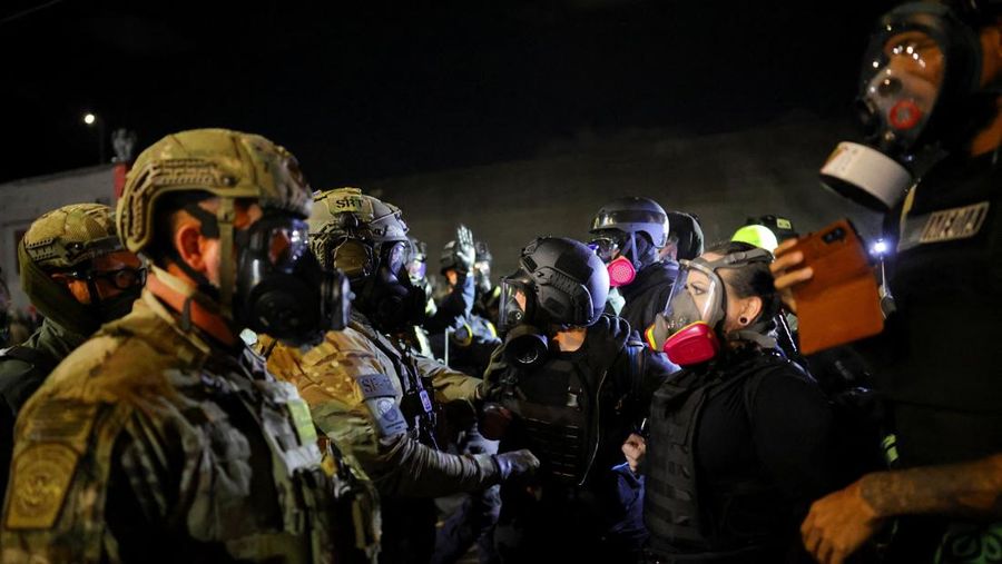 Para pengunjuk rasa berhadapan dengan petugas penegak hukum di luar markas besar Imigrasi dan Penegakan Bea Cukai AS (ICE) di Portland, Oregon, AS, 4 Oktober 2025. (REUTERS/Carlos Barria)