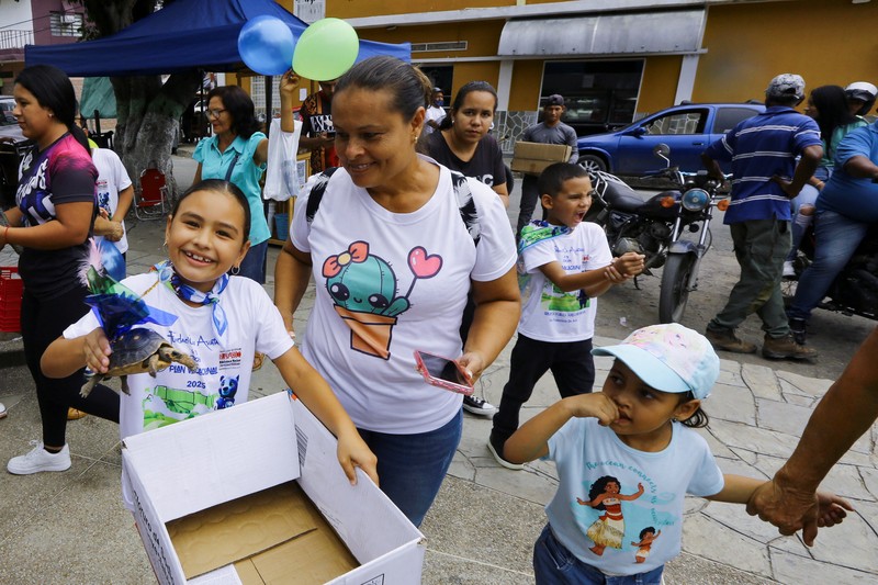 Seorang anak memegang Morrocoye, kura-kura darat asli Amerika Selatan, sebelum perlombaan kura-kura yang diadakan untuk merayakan hari raya Santo Fransiskus dari Assisi, santo pelindung hewan, di kota San Francisco de Asis, Venezuela, 3 Oktober 2025. (REUTERS/Juan Carlos Hernandez)