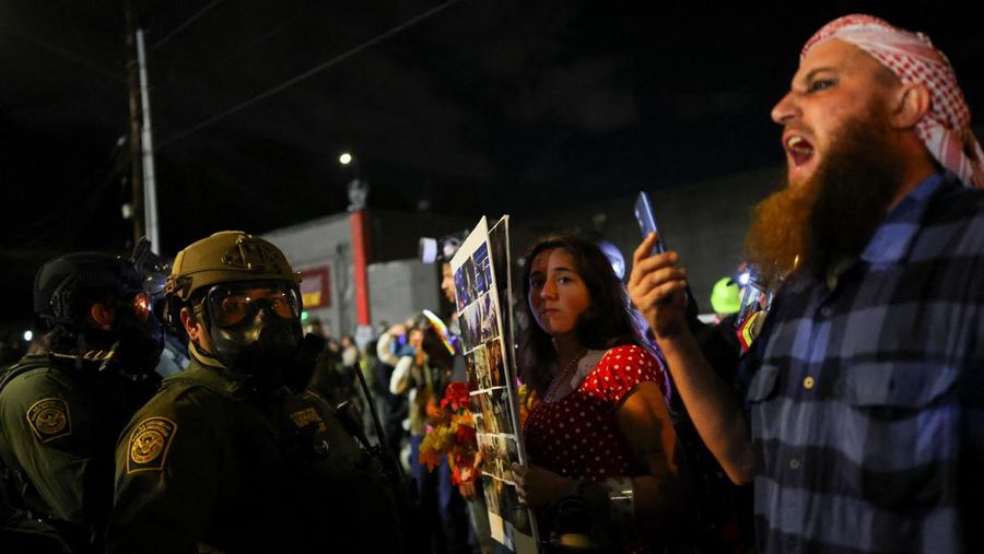 Para pengunjuk rasa berhadapan dengan petugas penegak hukum di luar markas besar Imigrasi dan Penegakan Bea Cukai AS (ICE) di Portland, Oregon, AS, 4 Oktober 2025. (REUTERS/Carlos Barria)
