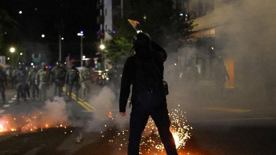 Para pengunjuk rasa berhadapan dengan petugas penegak hukum di luar markas besar Imigrasi dan Penegakan Bea Cukai AS (ICE) di Portland, Oregon, AS, 4 Oktober 2025. (REUTERS/Carlos Barria)