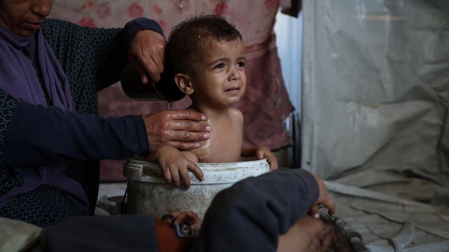 Foto Kombinasi, foto Kiri: Seorang wanita Palestina Iman Abdel Halim Abu Mutlaq menggendong bayi kembarnya yang baru lahir, Uday dan Hamza Abu Odah, di bangsal bersalin di Rumah Sakit Nasser, Khan Younis, Jalur Gaza selatan, 2 November 2023 dua tahun lalu. 
Foto Kanan: Iman Abdel Halim Abu Mutlaq menggendong putra kembarnya Uday dan Hamza Abu Odah di tenda tempat mereka berlindung, di daerah Mawasi, di Khan Younis di Jalur Gaza selatan, 18 September 2025.  (REUTERS/Mohammed Salem-Ramadan Abed)