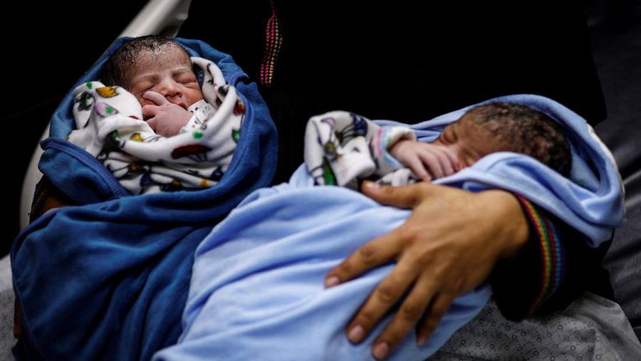 Foto Kombinasi, foto Kiri: Seorang wanita Palestina Iman Abdel Halim Abu Mutlaq menggendong bayi kembarnya yang baru lahir, Uday dan Hamza Abu Odah, di bangsal bersalin di Rumah Sakit Nasser, Khan Younis, Jalur Gaza selatan, 2 November 2023 dua tahun lalu. 
Foto Kanan: Iman Abdel Halim Abu Mutlaq menggendong putra kembarnya Uday dan Hamza Abu Odah di tenda tempat mereka berlindung, di daerah Mawasi, di Khan Younis di Jalur Gaza selatan, 18 September 2025.  (REUTERS/Mohammed Salem-Ramadan Abed)