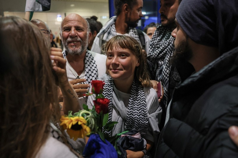 Aktivis Swedia Greta Thunberg, yang merupakan bagian dari Armada Sumud Global yang berupaya mengirimkan bantuan ke Gaza dan ditahan oleh Israel, memberi isyarat saat disambut oleh para pendukungnya saat kedatangannya di Bandara Internasional Eleftherios Venizelos Athena, di Athena, Yunani, 6 Oktober 2025. (REUTERS/Louisa Gouliamaki)
