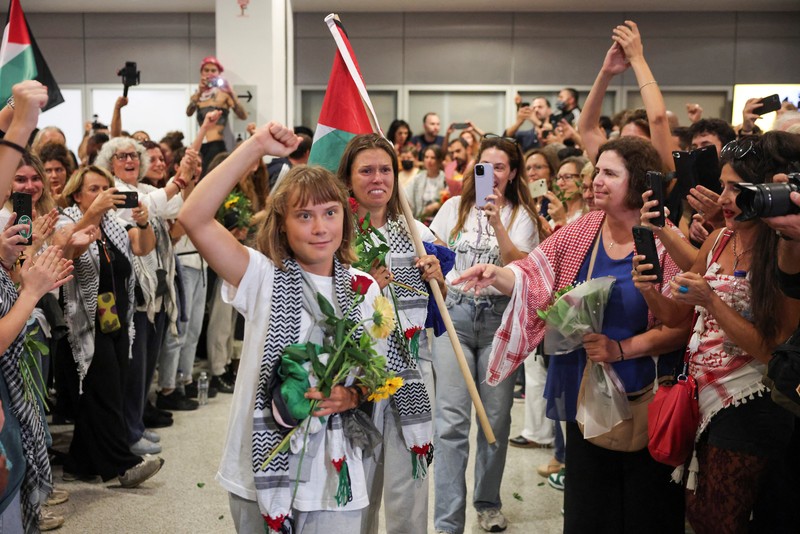 Aktivis Swedia Greta Thunberg, yang merupakan bagian dari Armada Sumud Global yang berupaya mengirimkan bantuan ke Gaza dan ditahan oleh Israel, memberi isyarat saat disambut oleh para pendukungnya saat kedatangannya di Bandara Internasional Eleftherios Venizelos Athena, di Athena, Yunani, 6 Oktober 2025. (REUTERS/Louisa Gouliamaki)