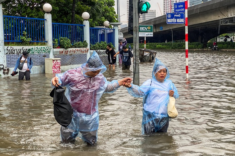 Orang-orang berjalan melalui jalan yang banjir di tengah hujan lebat akibat Topan Matmo, yang menyebabkan kendaraan terlantar, menutup sekolah, memindahkan kelas daring, dan menunda penerbangan ke dan dari Bandara Internasional Noi Bai, di Hanoi, Vietnam, 7 Oktober 2025. Orang-orang berjalan melalui jalan yang banjir di tengah hujan lebat akibat Topan Matmo, yang menyebabkan kendaraan terlantar, menutup sekolah, memindahkan kelas daring, dan menunda penerbangan ke dan dari Bandara Internasional Noi Bai, di Hanoi, Vietnam, 7 Oktober 2025. (REUTERS/Thinh Tien Nguyen)