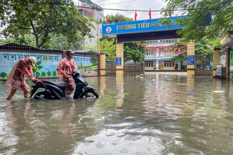 Orang-orang berjalan melalui jalan yang banjir di tengah hujan lebat akibat Topan Matmo, yang menyebabkan kendaraan terlantar, menutup sekolah, memindahkan kelas daring, dan menunda penerbangan ke dan dari Bandara Internasional Noi Bai, di Hanoi, Vietnam, 7 Oktober 2025. Orang-orang berjalan melalui jalan yang banjir di tengah hujan lebat akibat Topan Matmo, yang menyebabkan kendaraan terlantar, menutup sekolah, memindahkan kelas daring, dan menunda penerbangan ke dan dari Bandara Internasional Noi Bai, di Hanoi, Vietnam, 7 Oktober 2025. (REUTERS/Thinh Tien Nguyen)