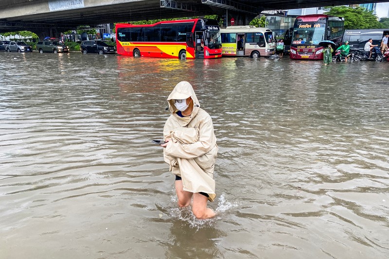 Orang-orang berjalan melalui jalan yang banjir di tengah hujan lebat akibat Topan Matmo, yang menyebabkan kendaraan terlantar, menutup sekolah, memindahkan kelas daring, dan menunda penerbangan ke dan dari Bandara Internasional Noi Bai, di Hanoi, Vietnam, 7 Oktober 2025. (REUTERS/Thinh Tien Nguyen)